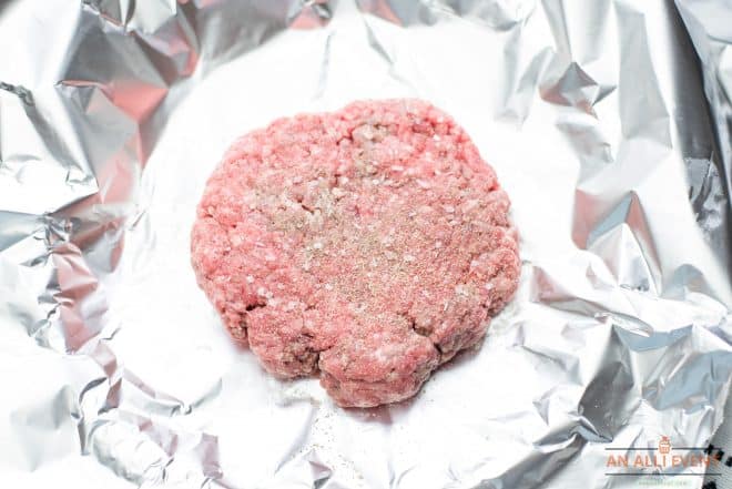 Hamburger Patty seasoned with salt and pepper, on foil lined plate