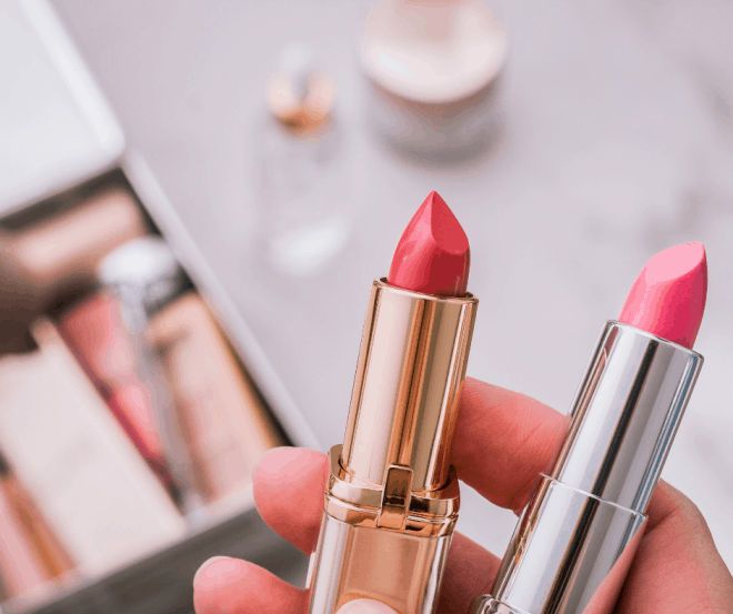 Makeup tips for women over 50 - a hand holding two tubes of pink lipstick