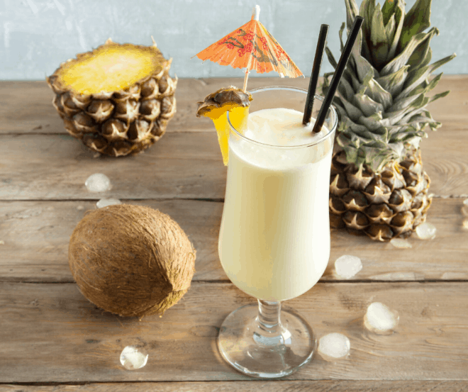 Breakfast Pina Colada Smoothie surrounded by coconuts and pineapples