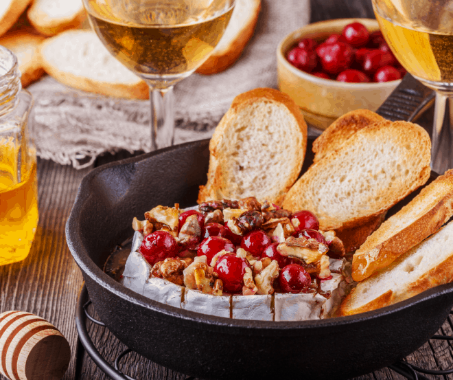 Platter with baked brie drizzled with honey and topped with walnuts with baguette slices