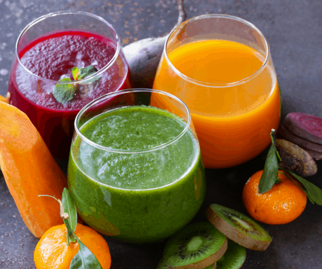 Fresh vibrant colored green juice, orange juice and beet juice in small glasses