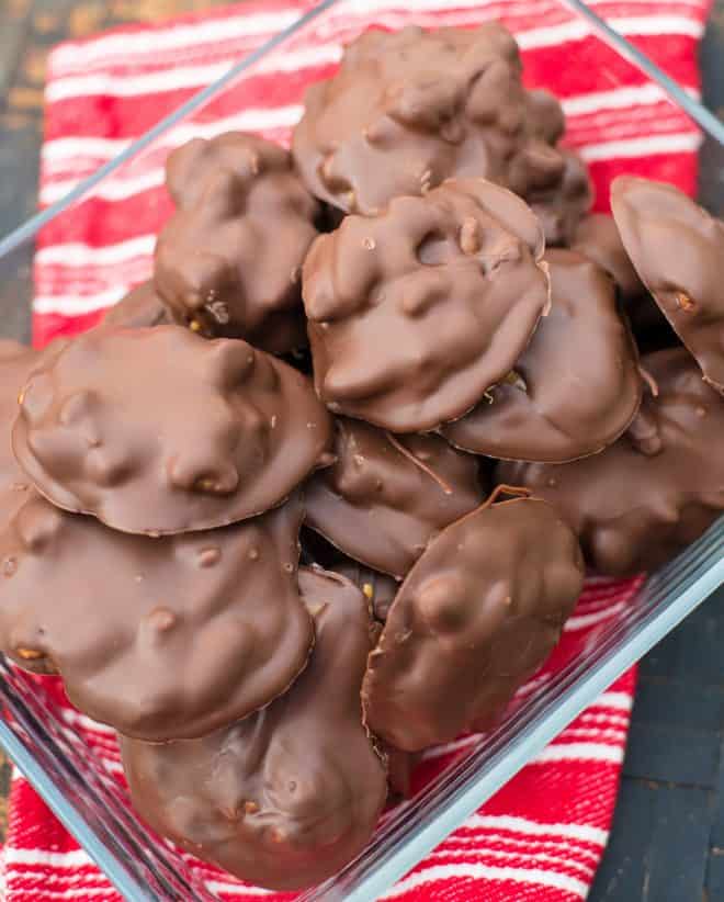 Caramel Pecan Turtles in a square glass container with a red and white striped towel in background