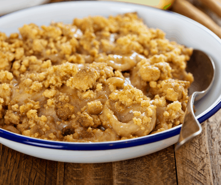 homemade caramel cobbler in a white bowl with a spoon