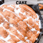 cinnamon cake in a black cast-iron skillet with a glaze drizzled on top
