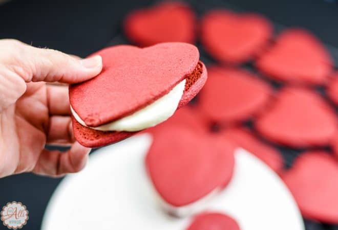 Adding frosting to Red Velvet Heart Shaped Cookies