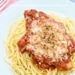 Simple Slow Cooker Chicken Parmesan served over spaghetti on a blue plate