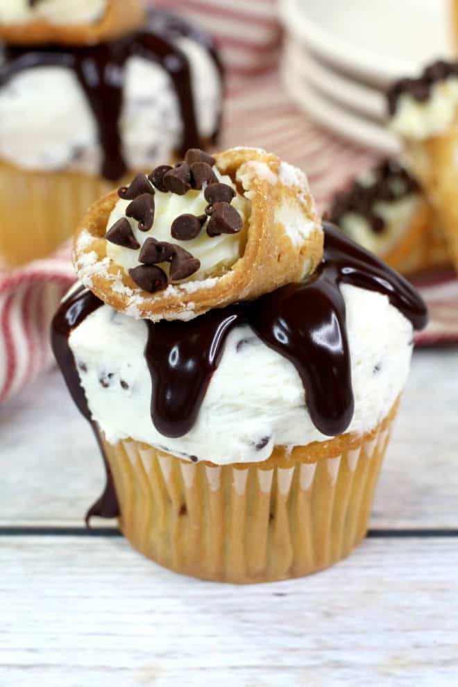 Cannoli Cupcakes With Mascarpone Frosting Topped with chocolate ganache and cannoli on a white table