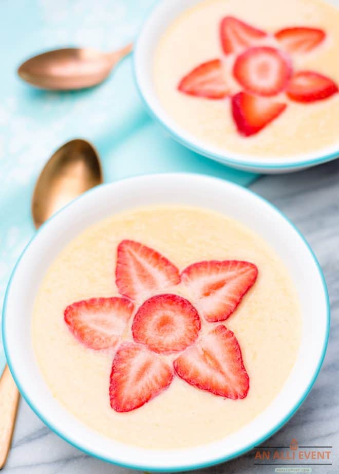 Two bowls of chilled cantaloupe soup with strawberry garnishes