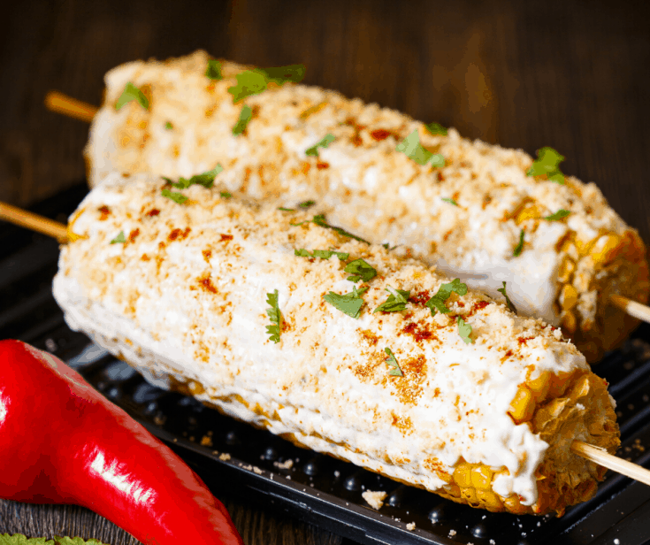 Grilled Corn On The Cob slathered in a sour cream mixture and sprinkled with cilantro