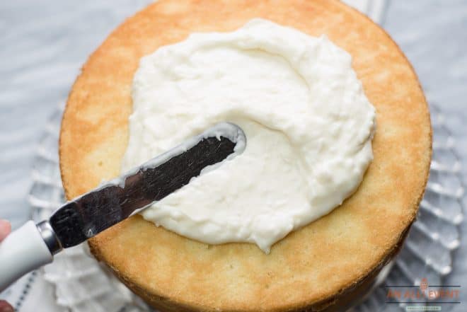 Coconut Frosting being spread between layers of coconut cake