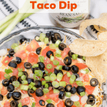 Bean Salad Taco Dip layered in a glass pie pan and topped with tomatoes, onions and sliced black olives