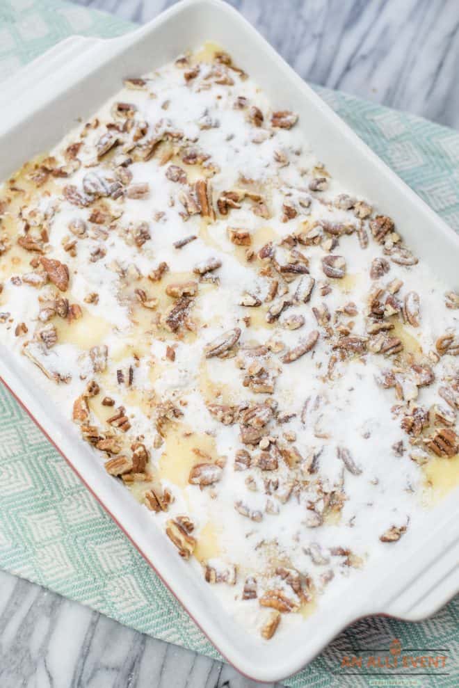 Pecans and granulated sugar sprinkled on top of cake mix in baking pan - Blueberry Crunch Dump Cake