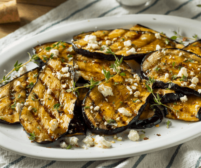 Sliced Eggplant Grilled and Topped With Feta Cheese on white platter