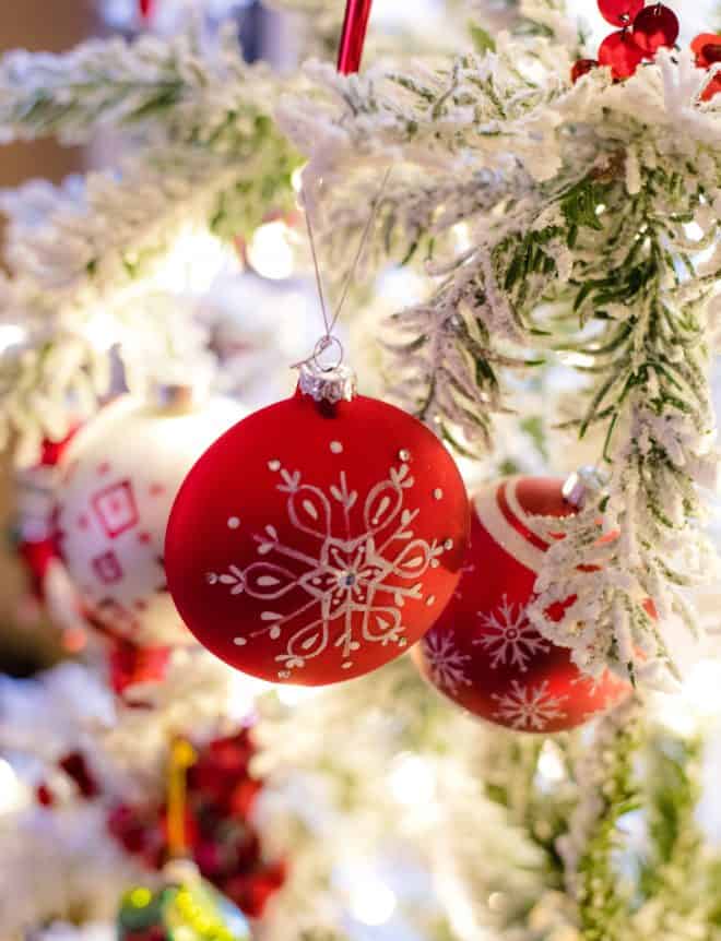 Red Ornament on Flocked Tree - Close Up Shot