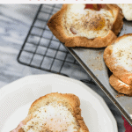 Bacon Egg and Cheese Toast Cups on baking rack with one toast cup on a small white plate with a fork
