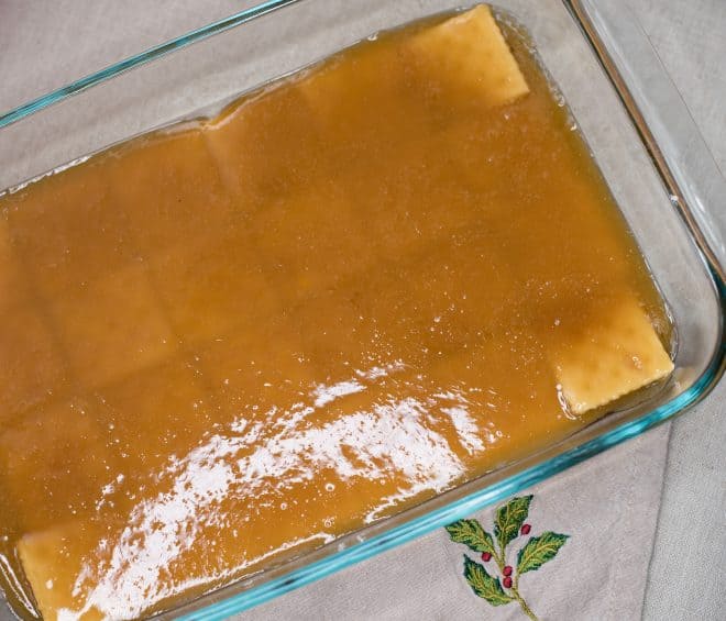 Toffee mixture poured over saltine crackers in 13x9 glass baking dish - to make Chocolate Crunch Candy