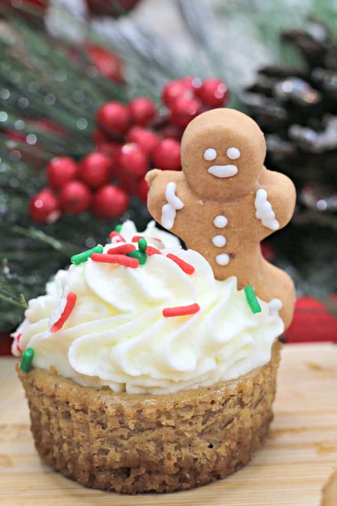 Mini Gingerbread Cheesecake topped with whipped cream, red and white sprinkles and an edible gingerbread man