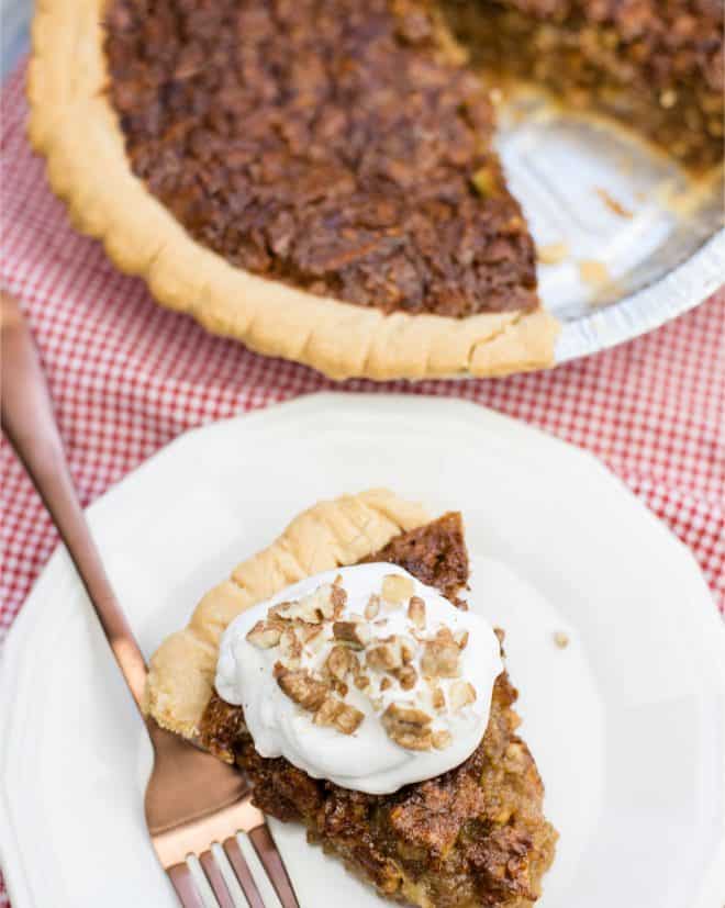 Caramel Pecan Pie Slice on a white plate with the rest of the pie in the background