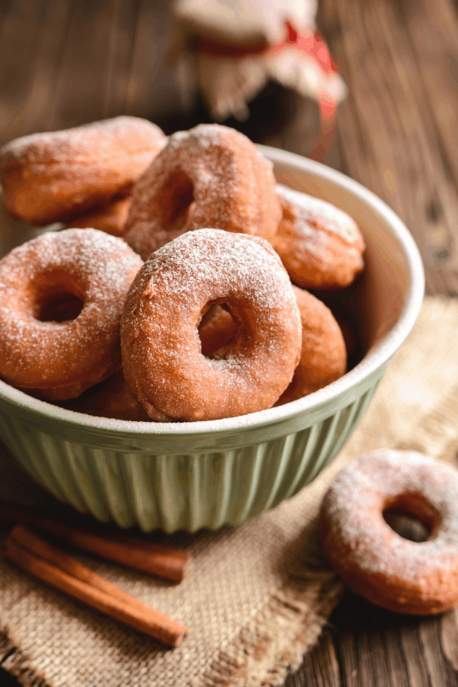 No-Yeast Buttermilk Doughnuts rolled in cinnamon sugar and placed in a green bowl