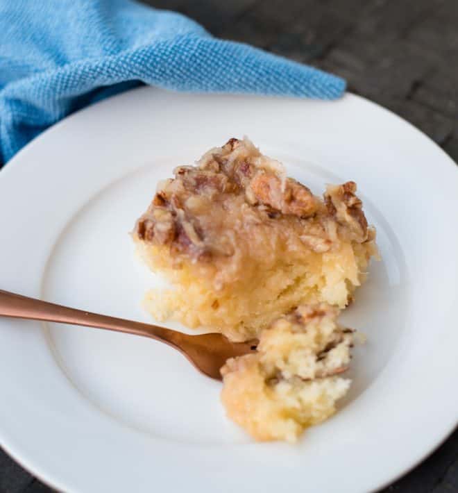 A Pineapple Sheet Cake square on a white plate with a blue napkin and gold fork