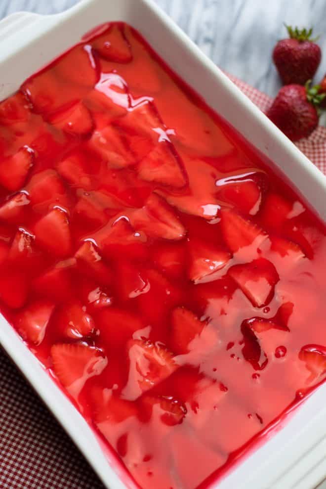 strawberry gelatin mixture poured over strawberries and cream cheese layer - this is the top layer for the strawberry dessert