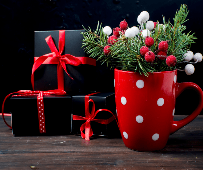 red Christmas mug with Christmas decorations and wrapped Christmas gifts in the background