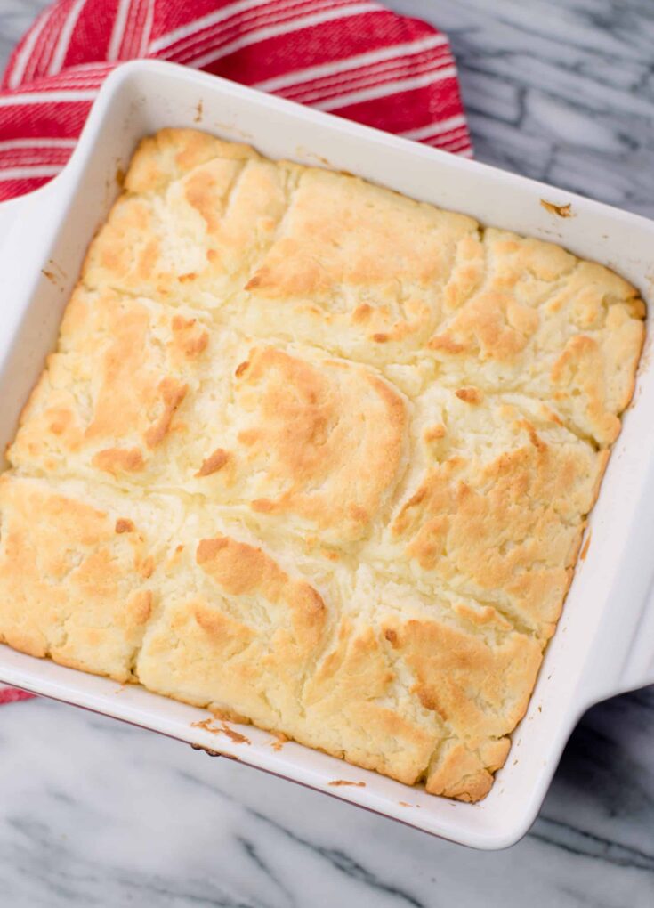 Butter Dipped Biscuits in a square baking pan with a red and white tea towel in the background