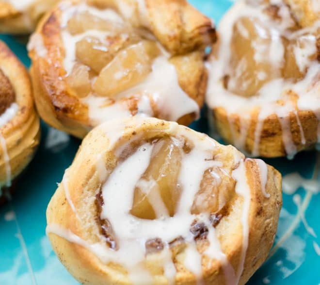 glaze drizzled over freshly baked cinnamon roll apple pies