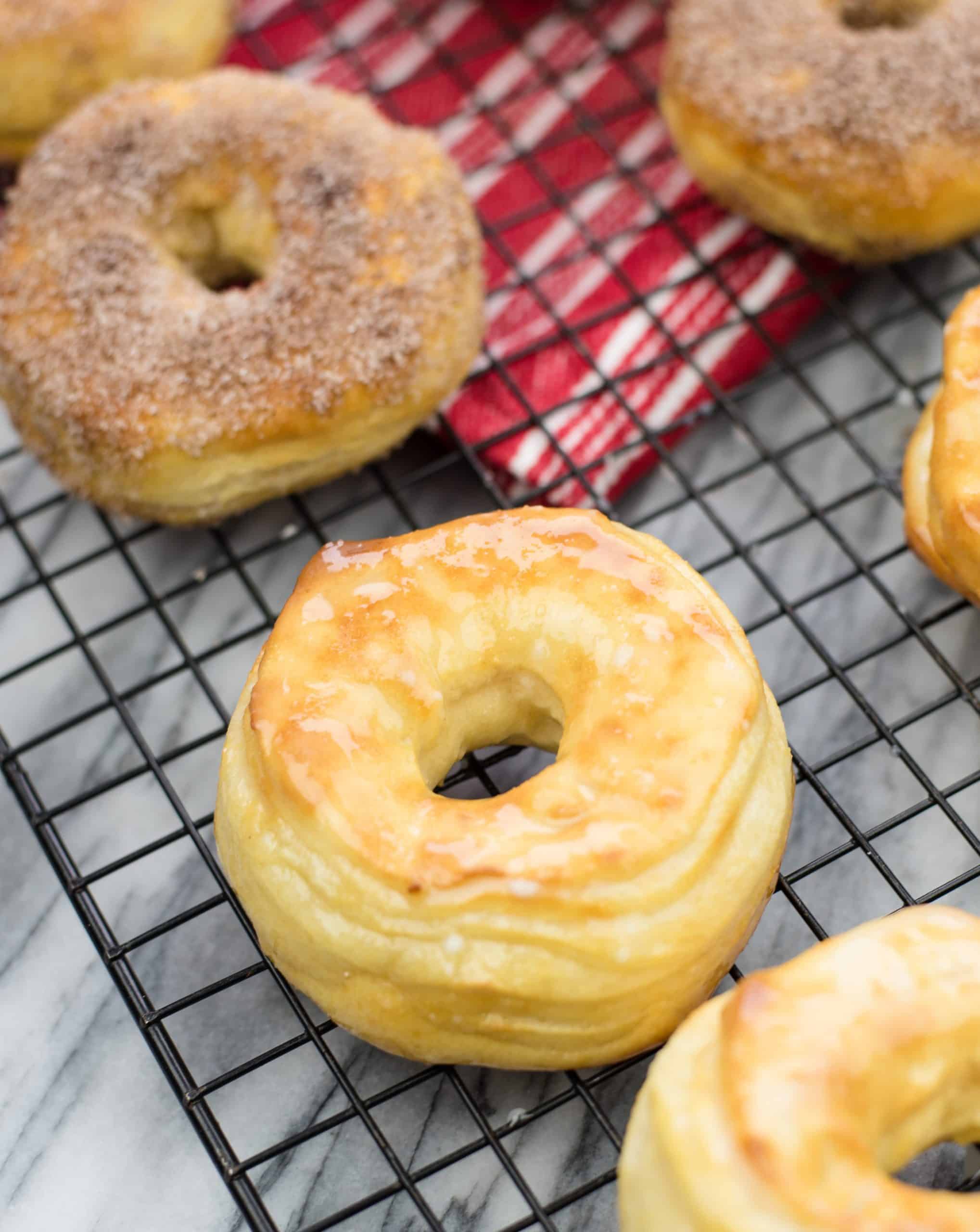 Air Fryer Doughnuts on Baking Rack - half of the doughnuts are dipped in cinnamon/sugar and the other half with traditional glaze