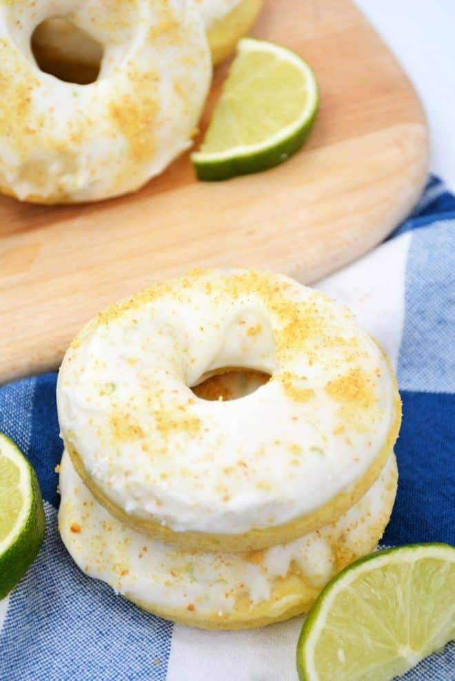 key lime baked doughnuts stacked up with a blue tea towel underneath