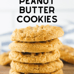 A stack of peanut butter cookies on a brown cutting board