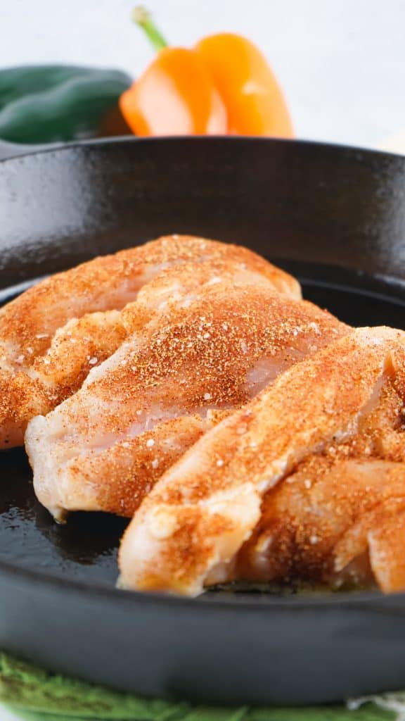 seasoned chicken breasts cooking in a cast iron skillet