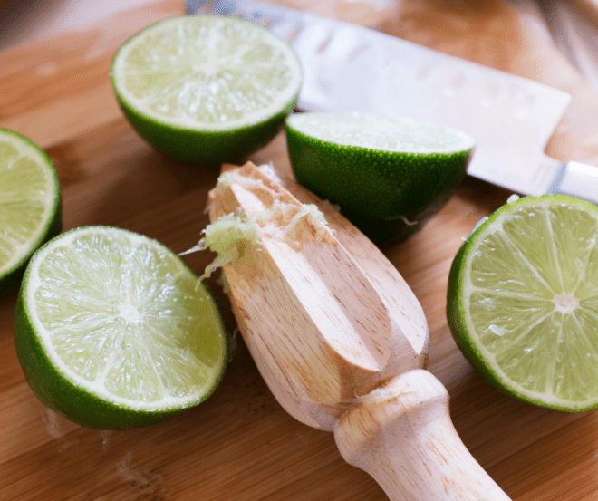 key limes and a citrus reamer on a cutting board
