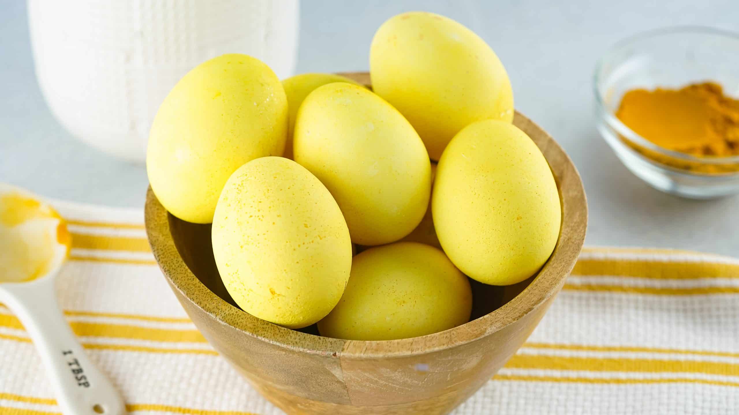 bright yellow turmeric dyed Easter Eggs in a brown bowl