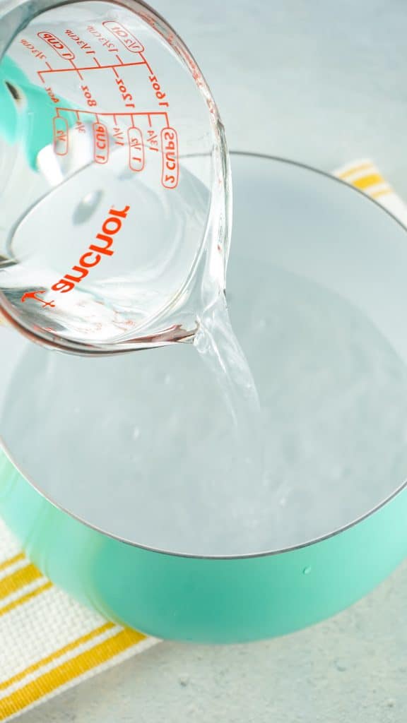 adding water to a stockpot using a measuring cup