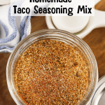 Easy Homemade Taco Seasoning Mix in a glass jar with a blue striped towel in the background and white measuring spoons