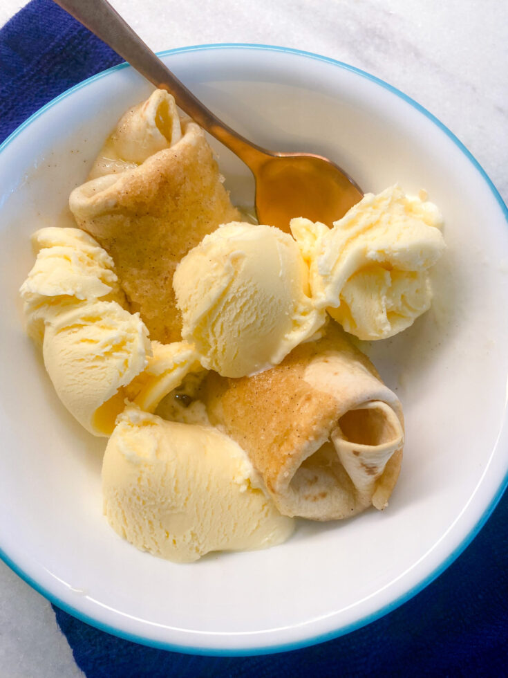 peach enchiladas in white serving bowl with vanilla ice cream