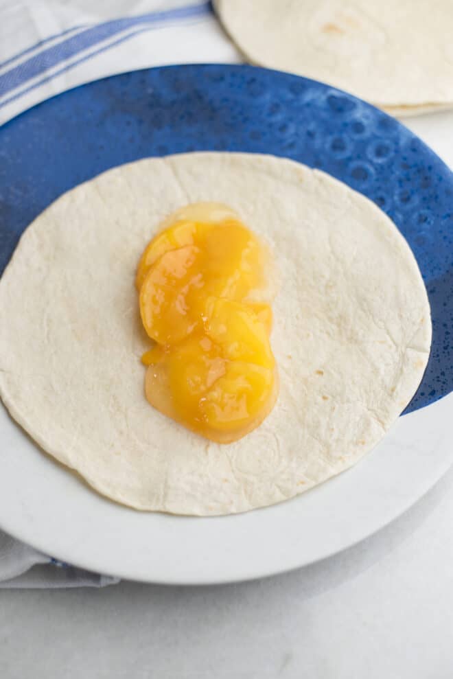 flour tortilla with peach pie filling spread down the center before rolling up