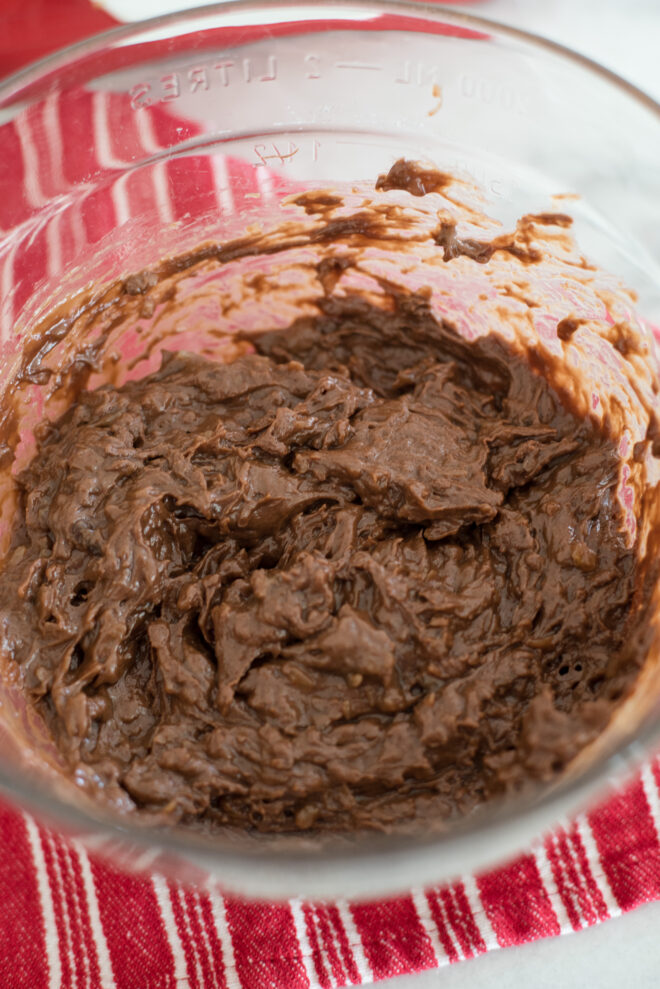 German chocolate frosting and melted chocolate morsels combined in a glass bowl