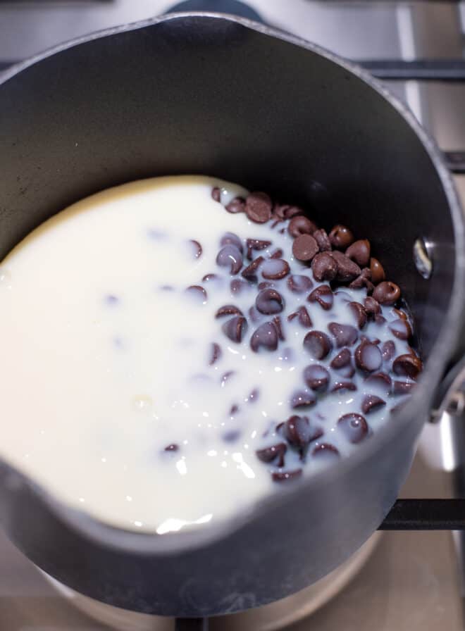 sweetened condensed milk and chocolate morsels melting together in a saucepan on top of the stove