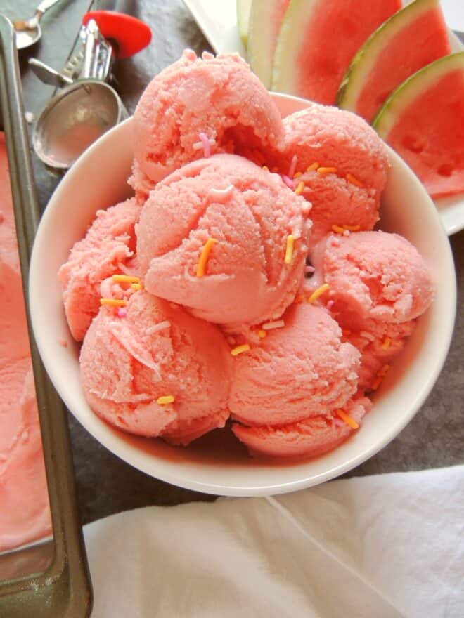a big white bowl full of scoops of watermelon ice cream
