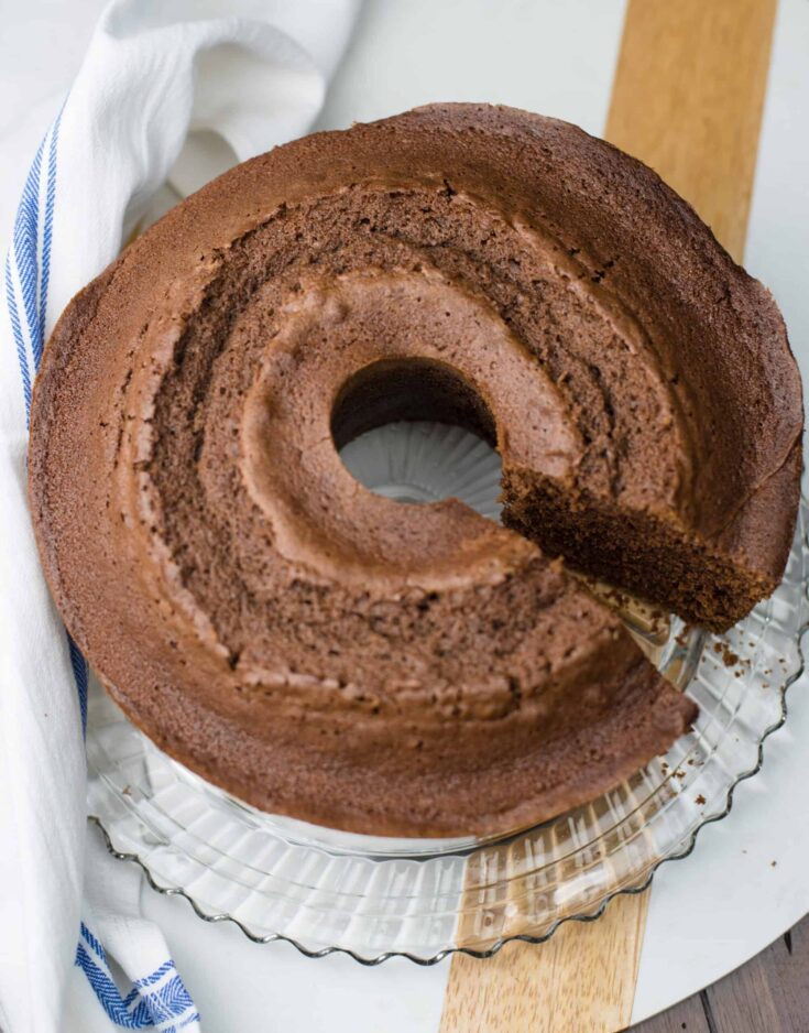 Chocolate Pound Cake on glass cake plate with one slice missing