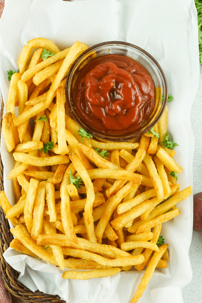 Easy Air Fryer French Fries in a basket with a bowl of ketchup
