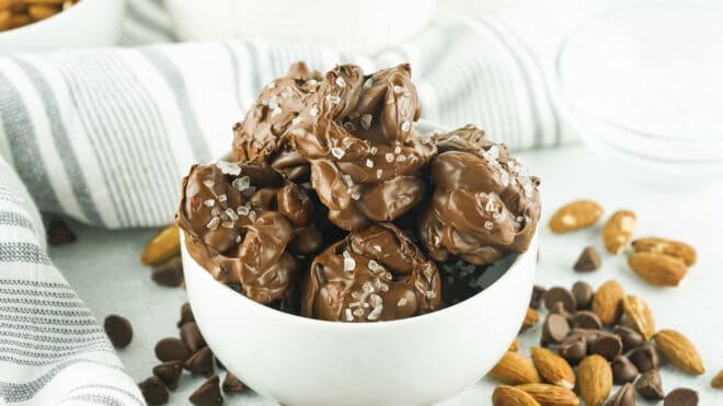 close up photo of hardened sea salt chocolate almond clusters in a white bowl