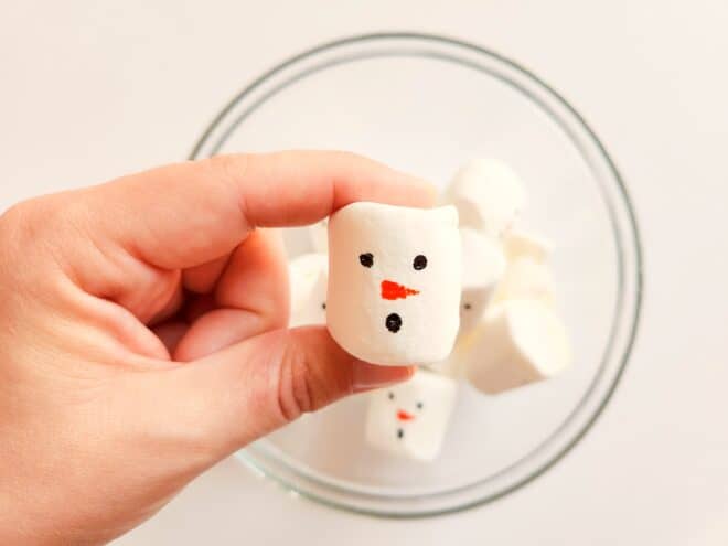 drawing the face of a snowman onto a marshmallow