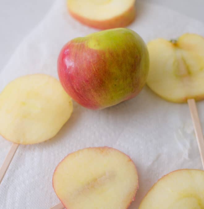 sliced apples with popsicle stick inserted in the bottom