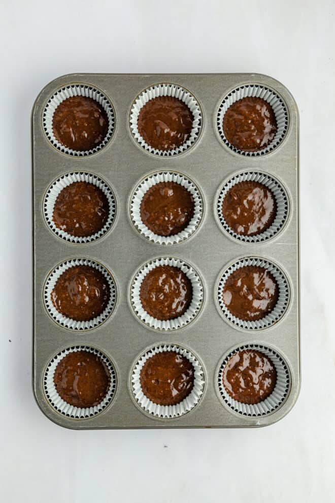 Chocolate cupcake batter in a 12-cup muffin tin before baking