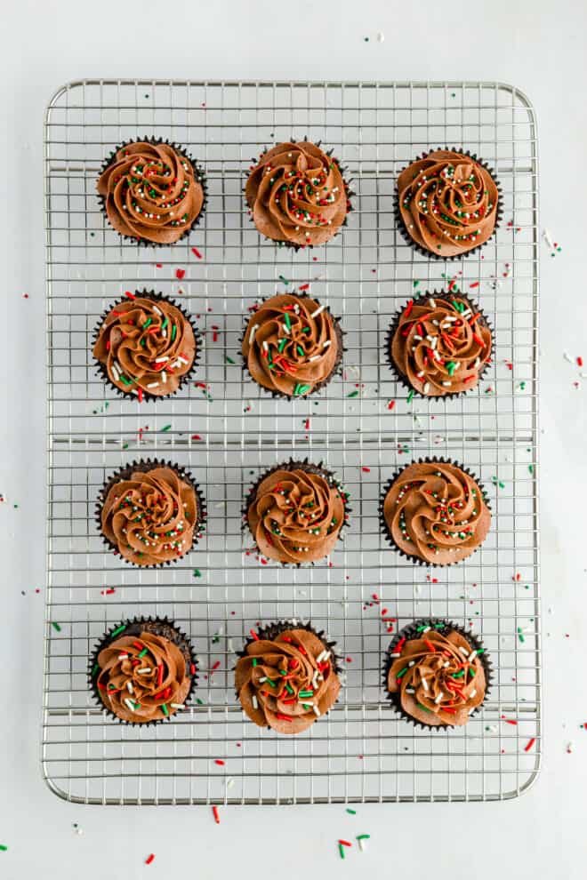 frosted chocolate cupcake with sprinkles on cooling rack
