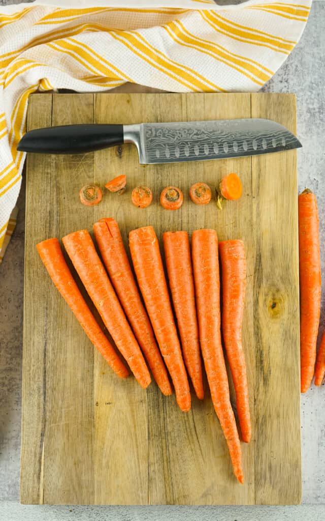 Cleaned carrots with ends cut off on cutting board.