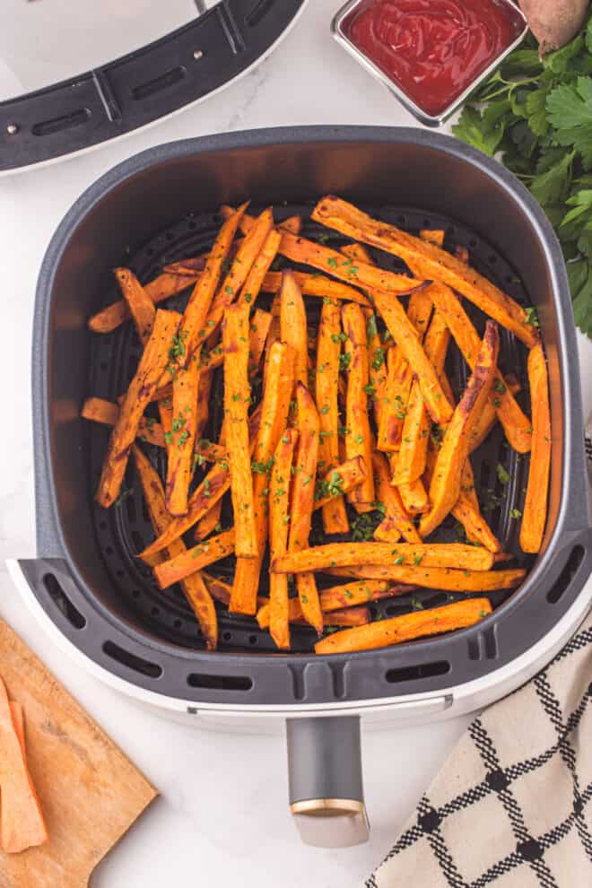 sweet potato fries in air fryer sprinkled with parsley